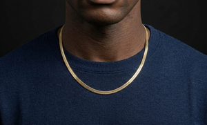Person wearing a gold chain necklace against a black background-J.Collins Jewelry