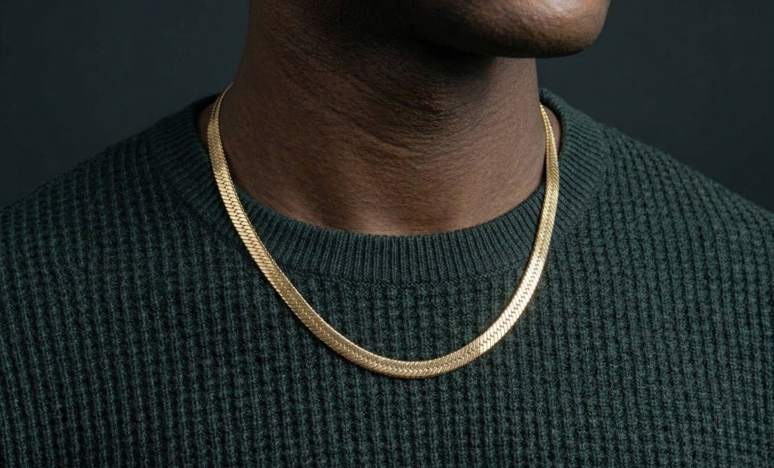 Gold herringbone necklace worn by a person against a dark background-J.Collins Jewelry