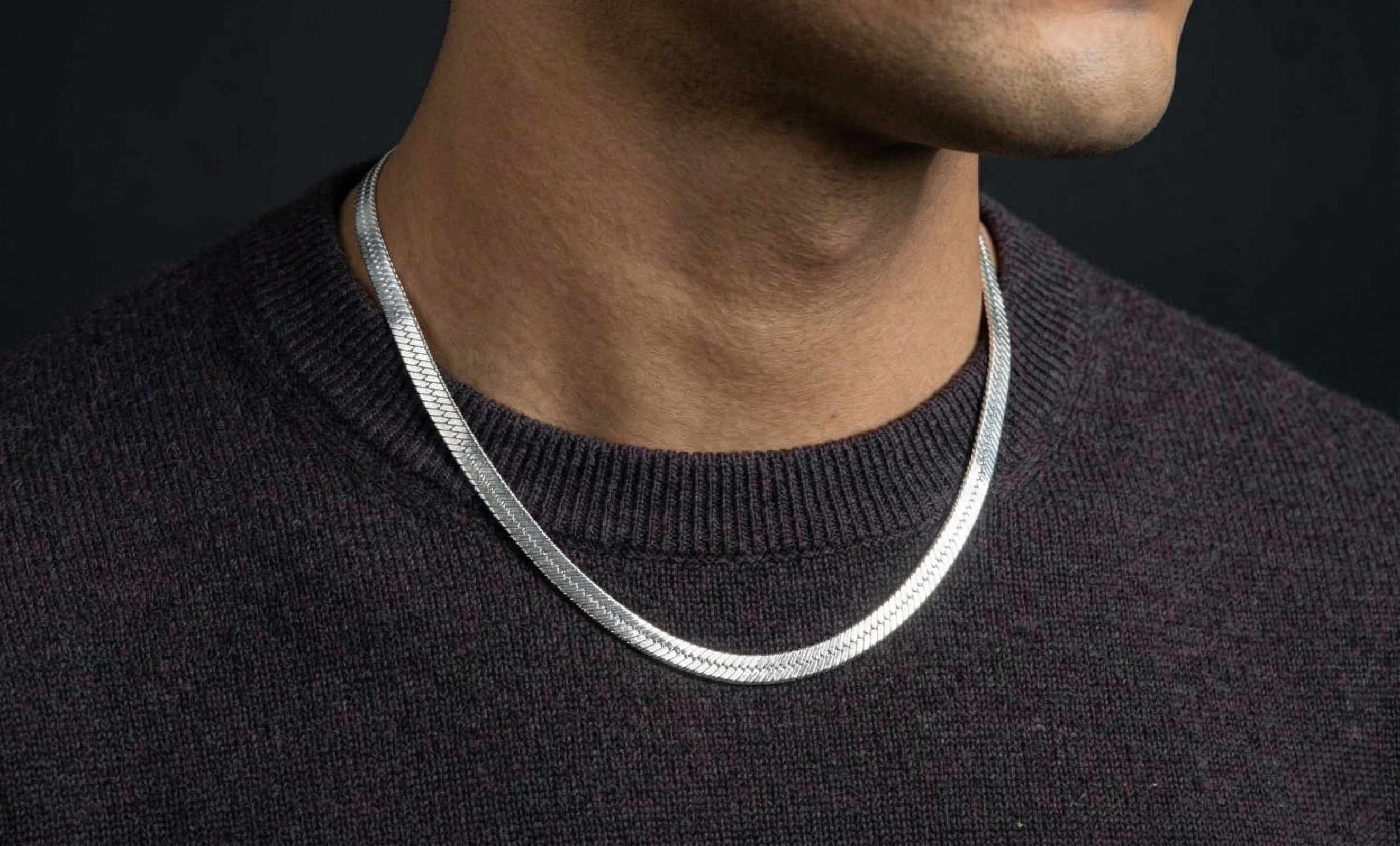 Silver herringbone necklace worn by a person against a dark background-J.Collins Jewelry