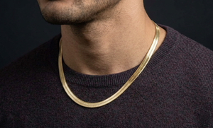 Man wearing a gold herringbone necklace against a dark background-J.Collins Jewelry