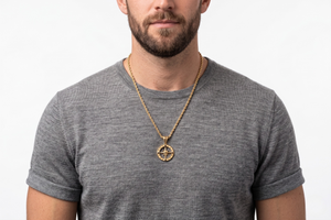 Man wearing a gray t-shirt and gold necklace with a compass pendant on a white background-J.Collins Jewelry