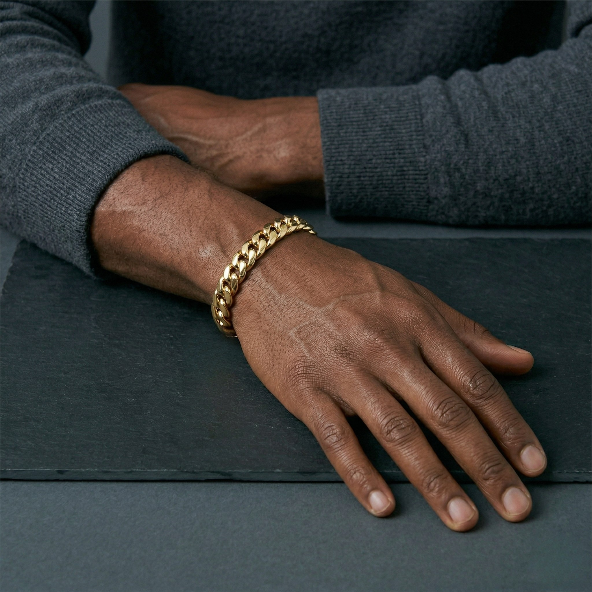 Gold bracelet on a person's wrist with a dark background-J.Collins Jewelry