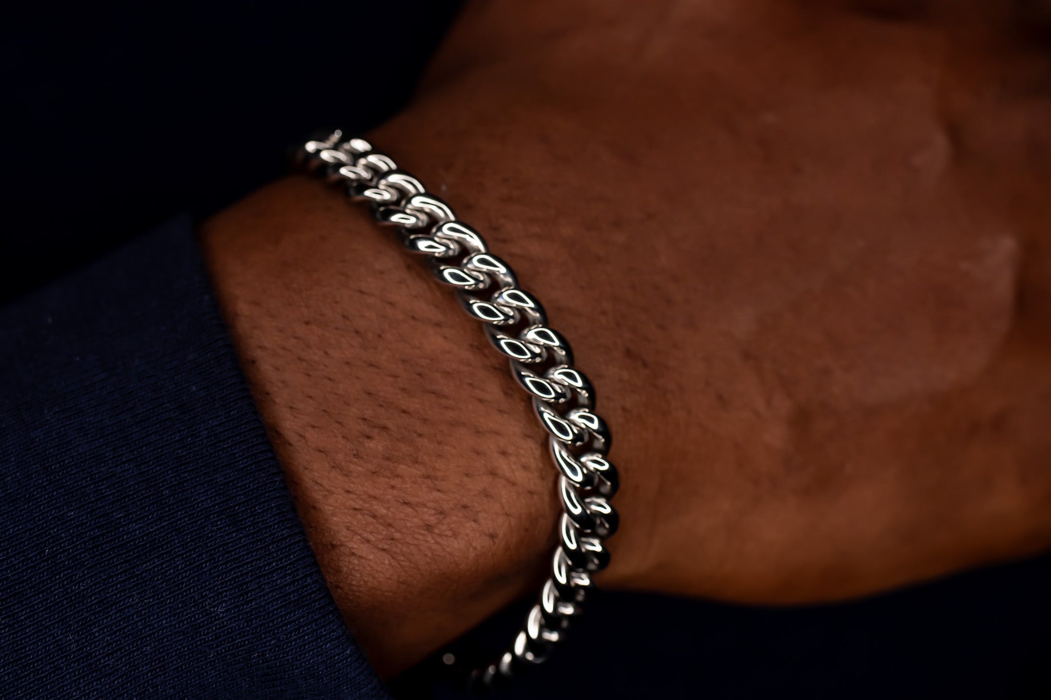 Silver chain bracelet on a wrist with a dark background-Iconic-Cuban-Bracelet-JCollins-Jewelry