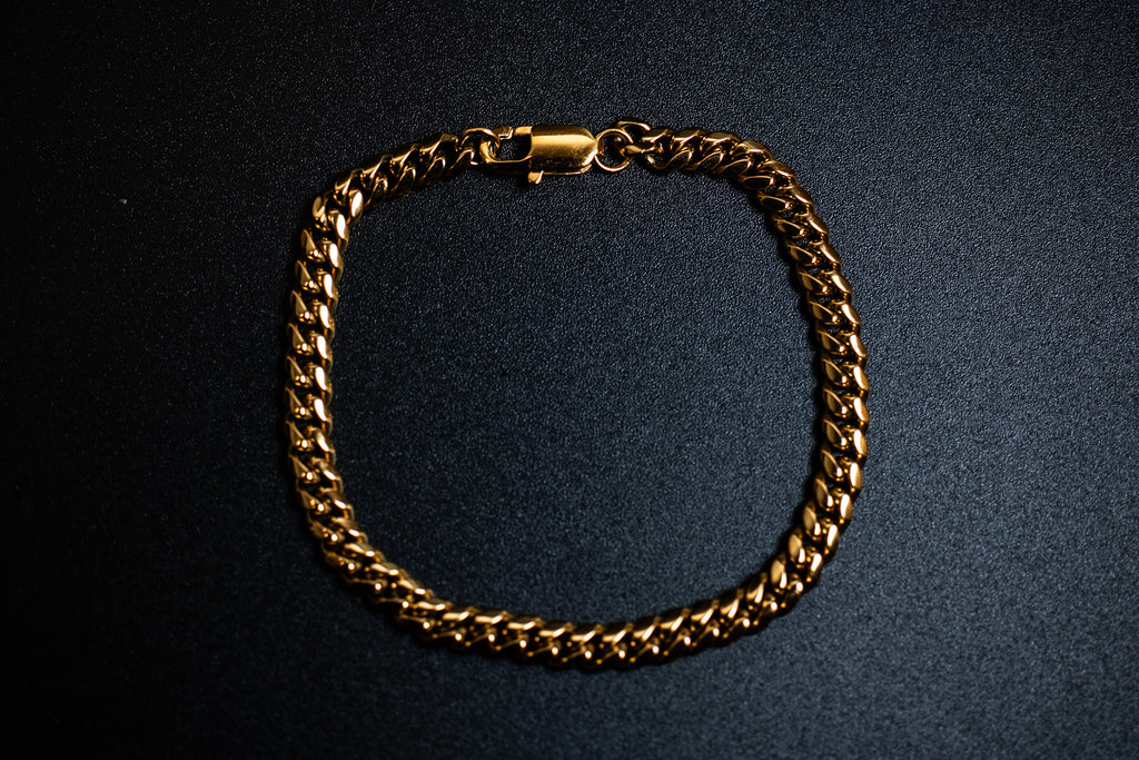 Gold chain bracelet on a dark background-Iconic-Cuban-Bracelet-JCollins-Jewelry
