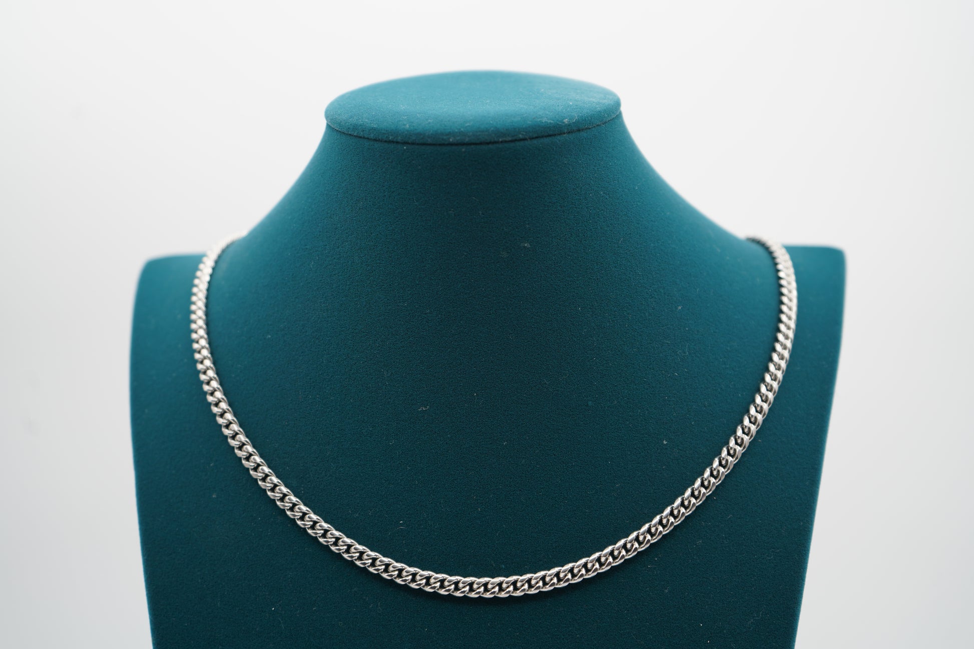 Silver chain necklace on a green mannequin bust against a white background-Iconic-Cuban-Chain-JCollins-Jewelry