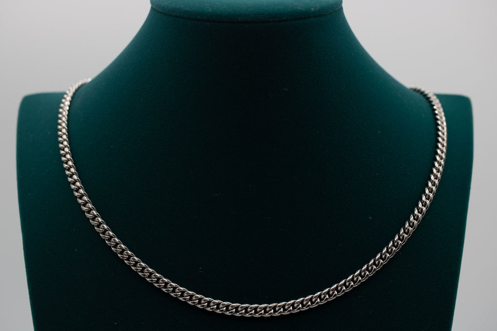 Silver chain necklace on a green mannequin bust against a gray background-Iconic-Cuban-Chain-JCollins-Jewelry