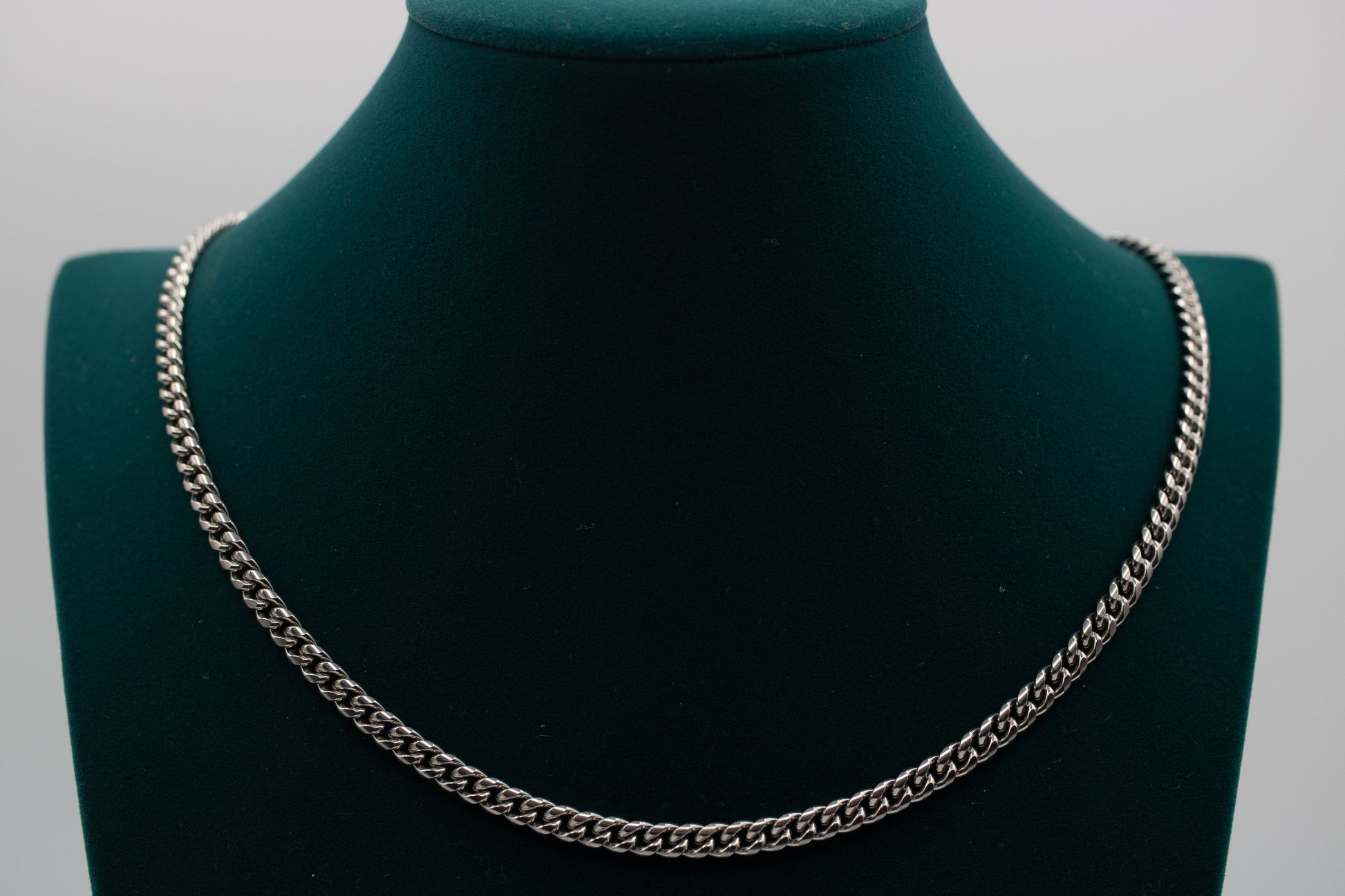 Silver chain necklace on a green mannequin bust against a gray background-Iconic-Cuban-Chain-JCollins-Jewelry