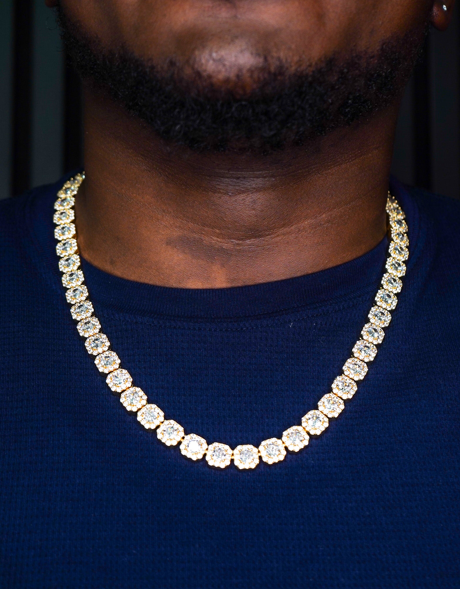 Gold chain necklace worn by a person against a dark background-10mm-Tennis-Chain-JCollins-Jewelry