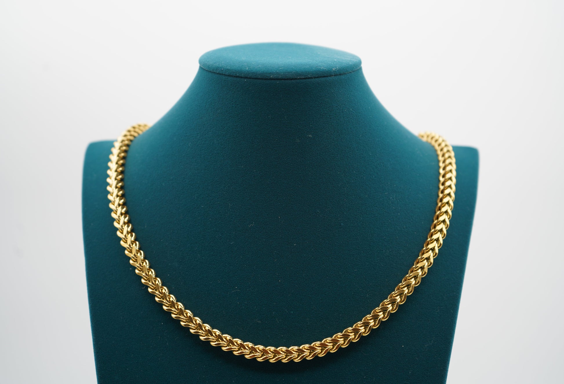 Gold chain necklace on a green mannequin bust with a white background -Signature-Franco-Chain-JCollins-Jewelry