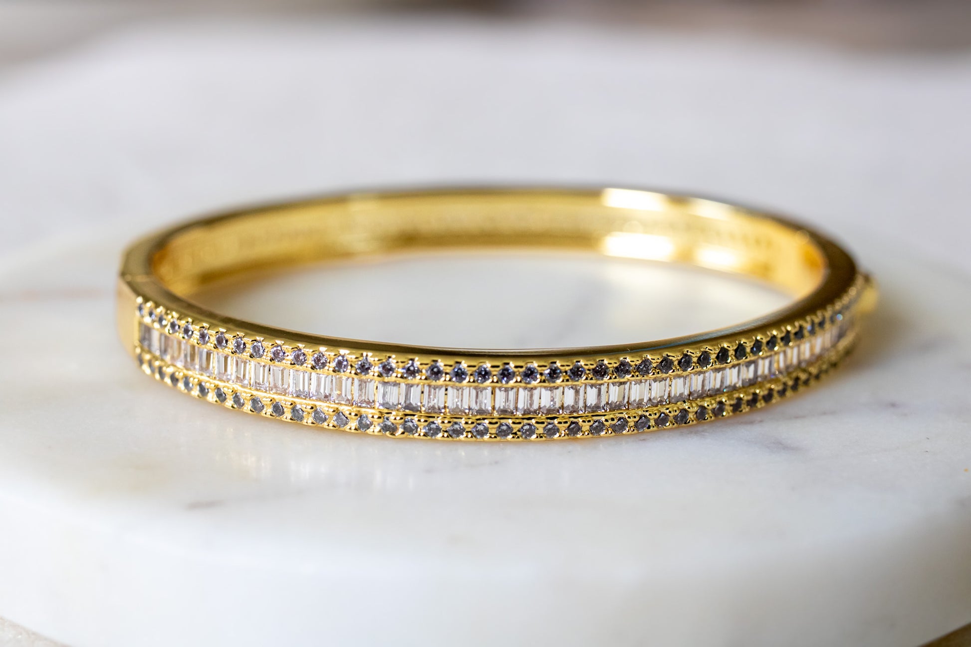 Gold bracelet with embedded stones on a marble surface-Lustre-Line-Cuff-J.Collins Jewelry