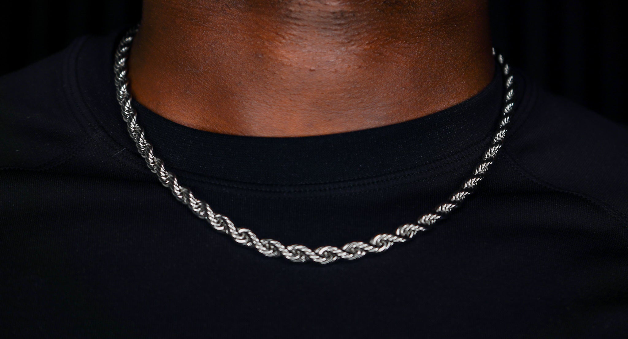 Silver rope chain necklace on a black background