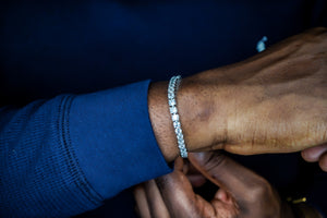 Close-up of a person's wrist wearing a diamond bracelet with a dark background-Tennis-Silver-Bracelet-JCollins-Jewelry