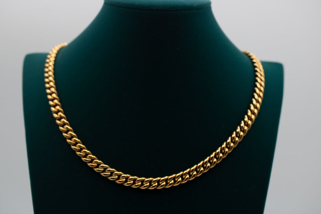 Gold chain necklace on a green mannequin bust against a gray background-Iconic-Cuban-Chain-JCollins-Jewelry