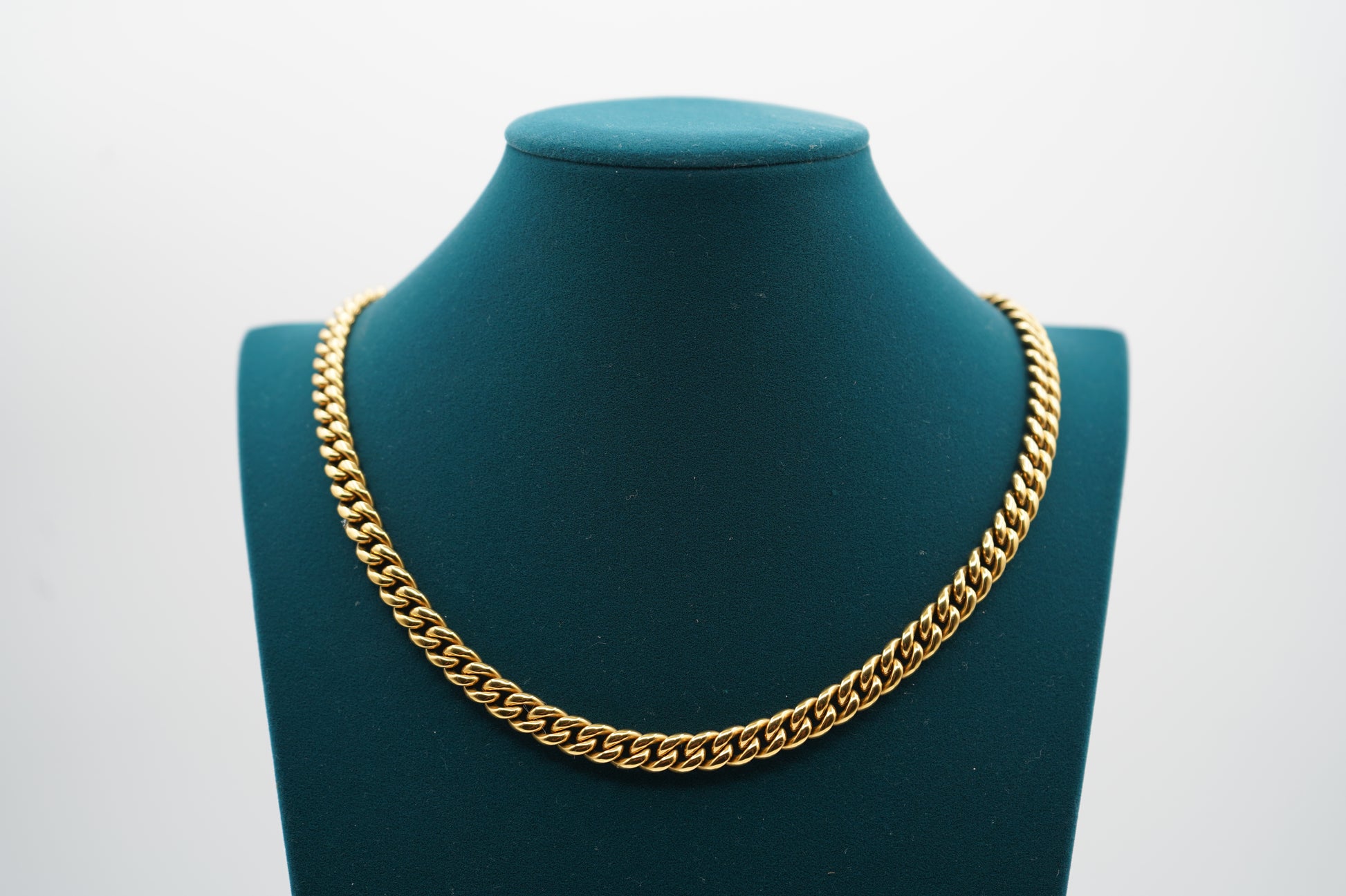 Gold chain necklace on a green mannequin bust against a white background-Iconic-Cuban-Chain-JCollins-Jewelry