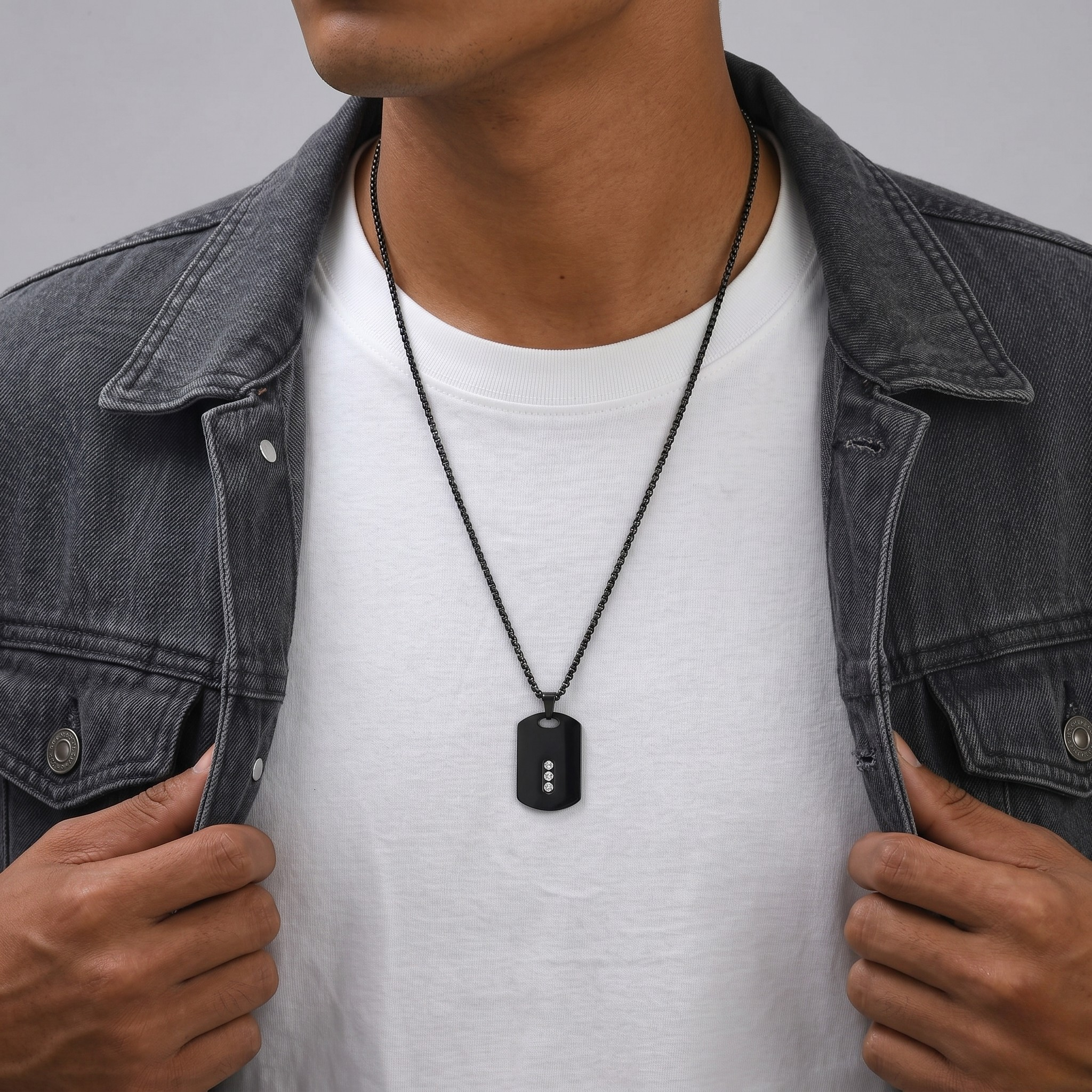 Person wearing a black dog tag necklace with a gray jacket and white shirt-J.Collins Jewelry