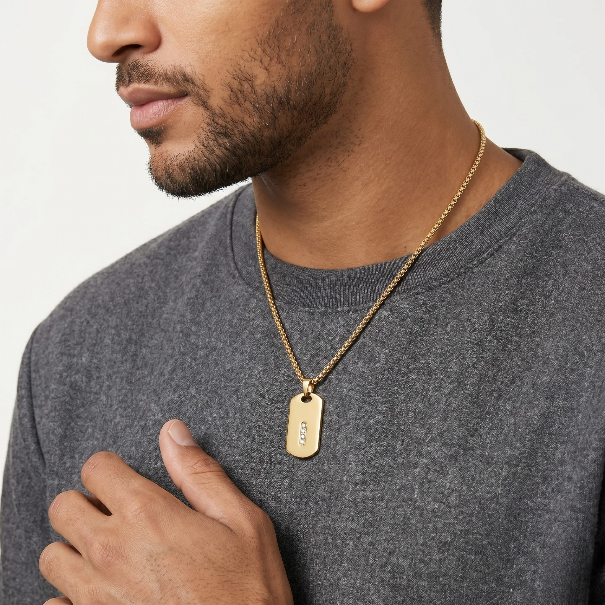 Man wearing a gold necklace with a tag on a plain background-J.Collins Jewelry