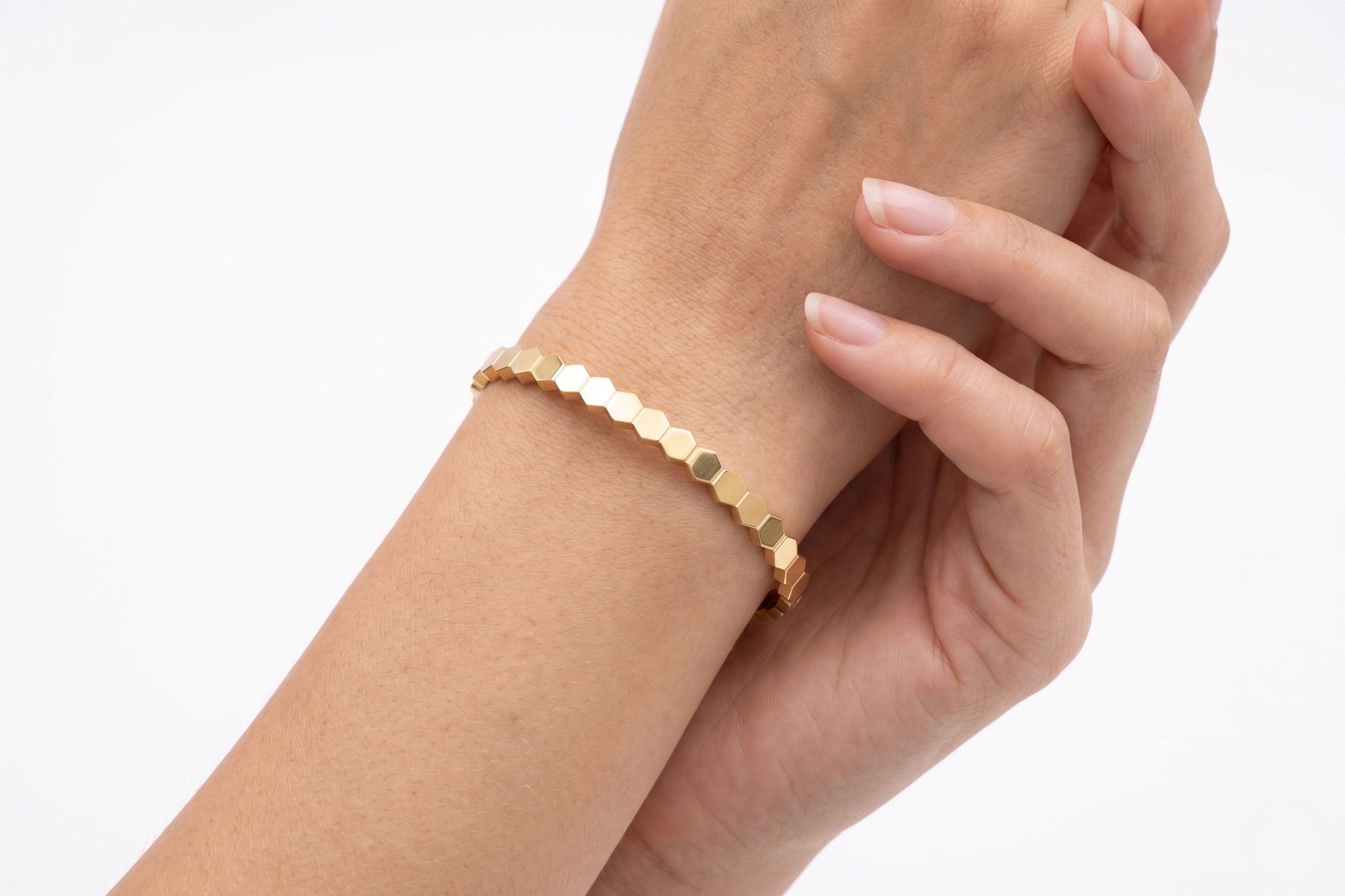 Gold bracelet on a wrist with a plain background-J.Collins Jewelry