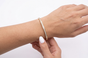 Person wearing a gold bracelet on a plain background- J.Collins Jewelry
