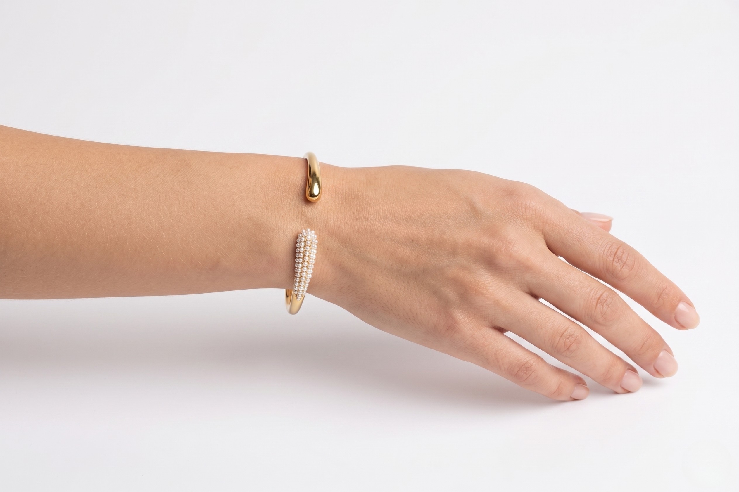Hand wearing two gold bracelets on a white background-J.Collins Jewelry
