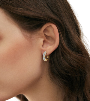 Close-up of a person wearing a gold hoop earring with a clear gemstone-J.Collins Jewelry
