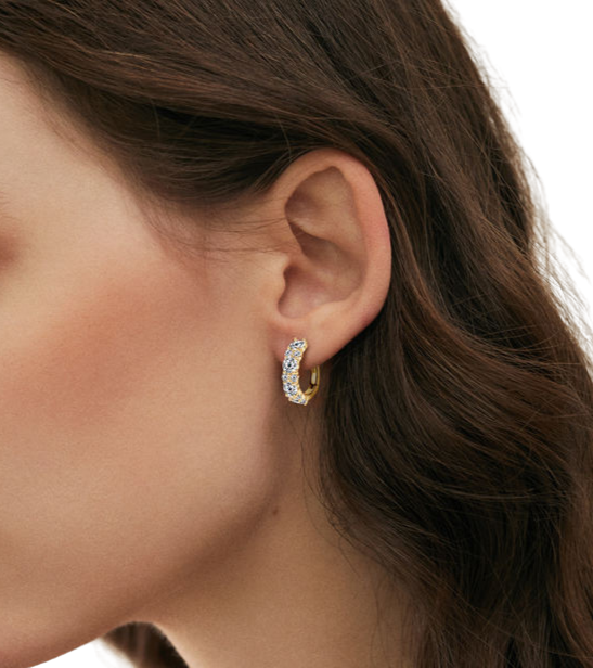 Close-up of a person wearing a gold hoop earring with a clear gemstone-J.Collins Jewelry
