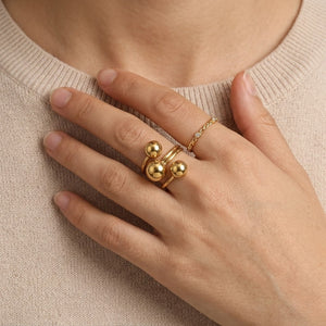 Model wearing a statement gold open sphere ring paired with a delicate gold chain band on her index finger | J.Collins Jewelry
