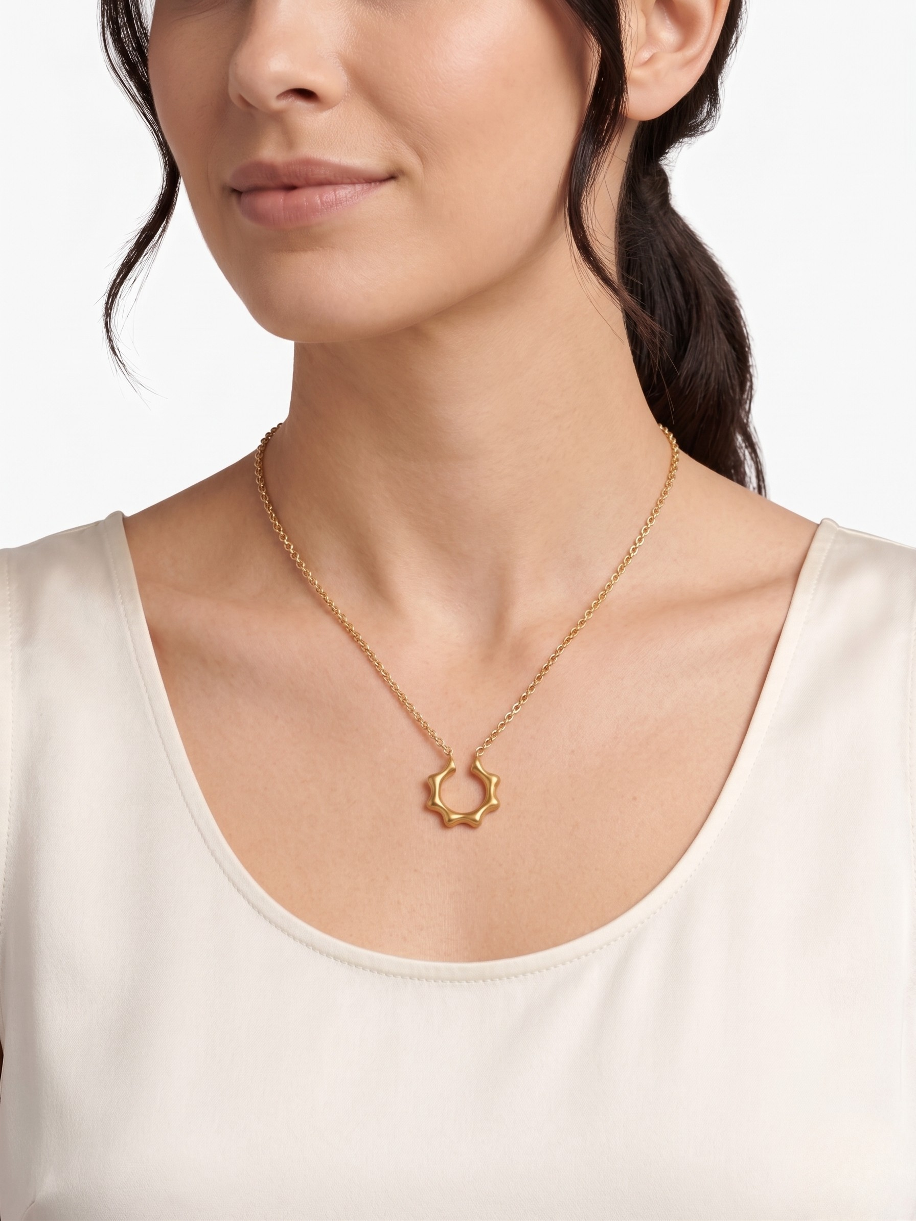Gold star-shaped pendant necklace on woman wearing a white top, side profile view