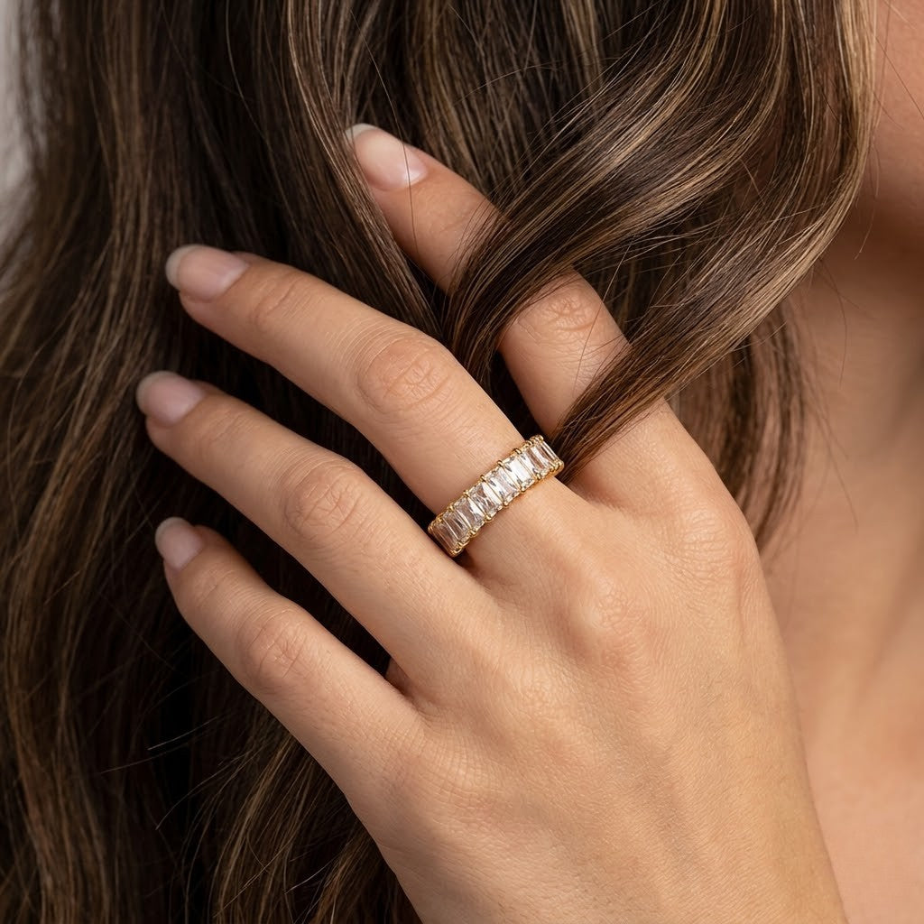 Gold opulent bar ring worn on a woman's finger with long brown hair in lifestyle setting