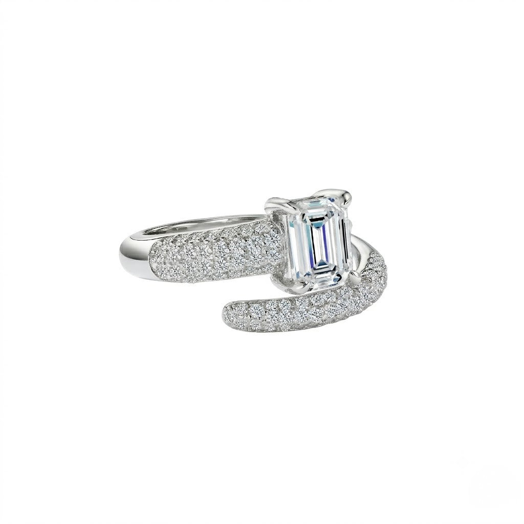 A silver-toned ring featuring a central emerald-cut clear gemstone and pavé-set side stones, shown on a plain white background - J.Collins Jewelry