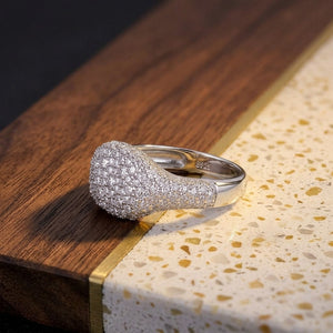 S925 sterling silver pavé dome signet ring encrusted with micro cubic Moissanite  crystals featuring visible inner hallmark stamp resting on a wooden block with speckled terrazzo accent by J.Collins
