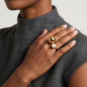 Woman wearing gold and pearl ring on right hand, gray sleeveless top context