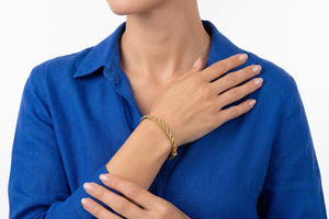 Person wearing a blue shirt with a gold bracelet on a white background-J.Collins Jewelry