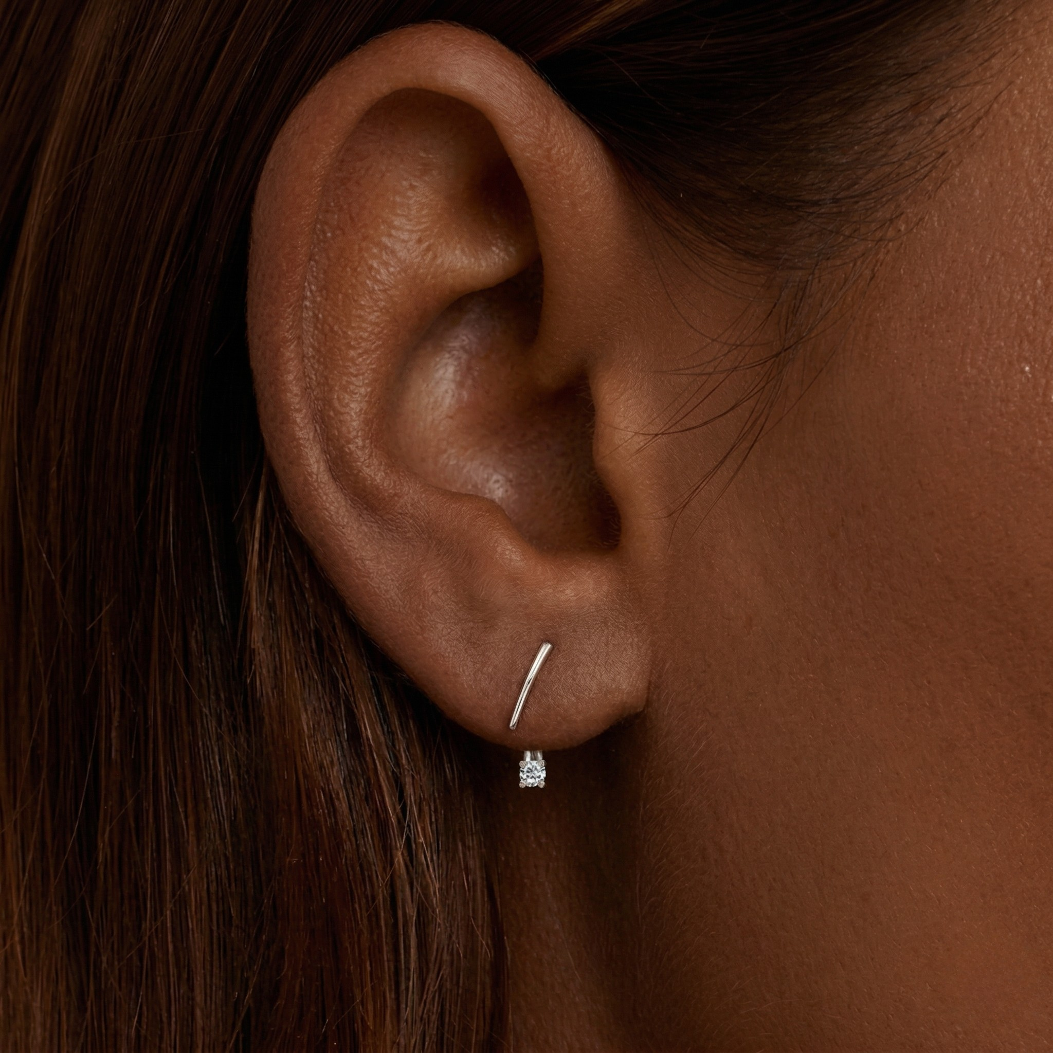 Woman with fancy hair wearing a silver earring on a white background