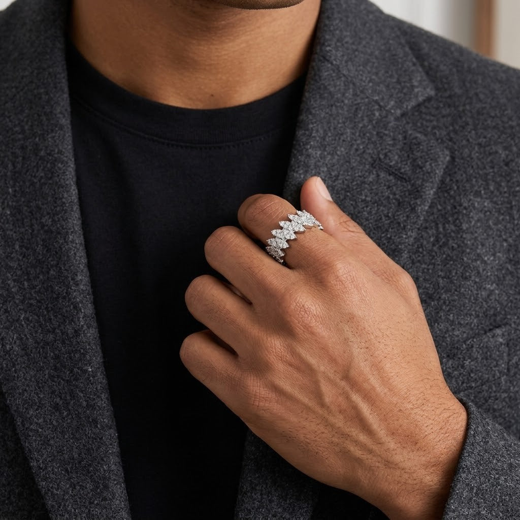 A close-up of a person wearing a silver ring with a floral or leaf-like pattern on one finger, dressed in a black t-shirt and a textured gray blazer - J.Collins Jewelry