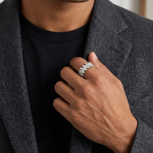 A close-up of a person wearing a silver ring with a floral or leaf-like pattern on one finger, dressed in a black t-shirt and a textured gray blazer - J.Collins Jewelry