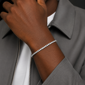A close-up of a person's wrist wearing a sparkling silver tennis bracelet, styled with a gray zip-up jacket over a white shirt - J.Collins Jewelry