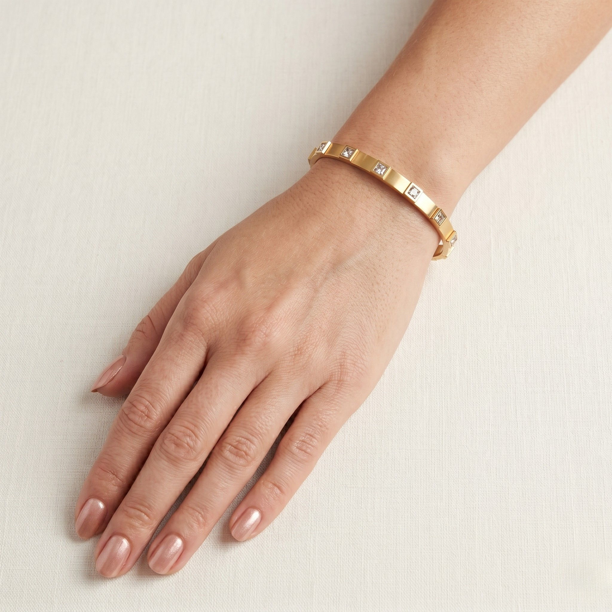 Gold bracelet on a wrist with a plain background-J.Collins Jewelry