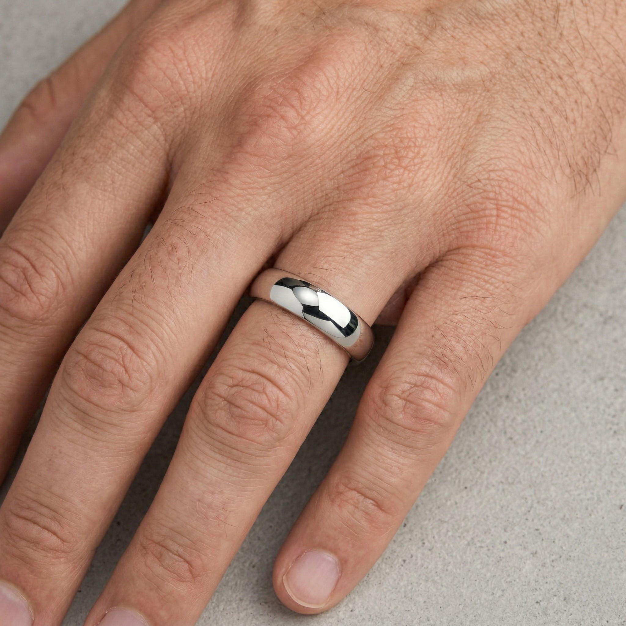 Silver High-Polish Mirror Finish Wide Dome Court Wedding Band Ring Worn on Male Hand Against Stone Surface - J. Collins Jewelry 