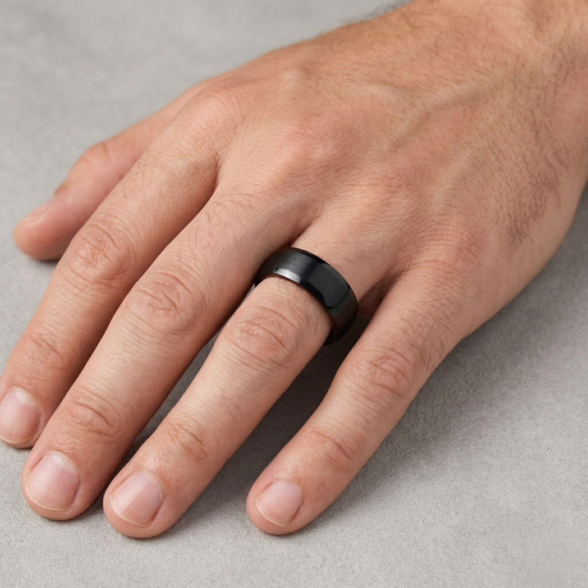 Hand wearing a black smart ring on a gray background