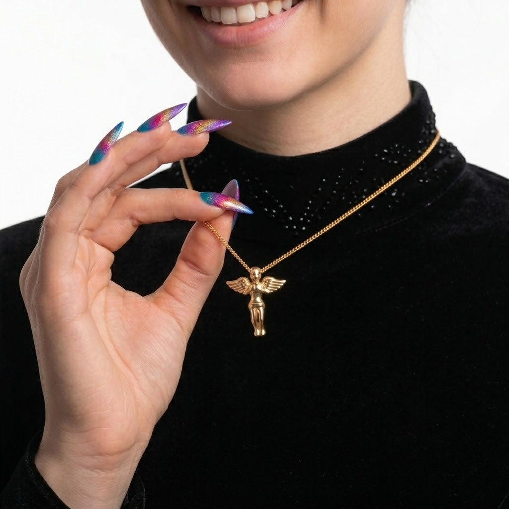 A close-up of a person wearing a black turtleneck and holding a gold necklace with a winged figure pendant against a white background - J.Collins Jewelry