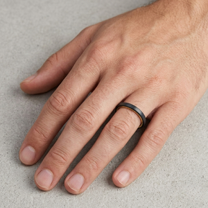 Hand wearing a black ring on a light gray background