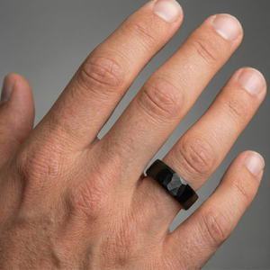 Hand wearing a black ring on a gray background-J.Collins Jewelry