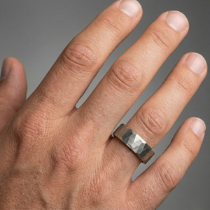 Hand wearing a silver ring with a textured band on a gray background-J.Collins Jewelry
