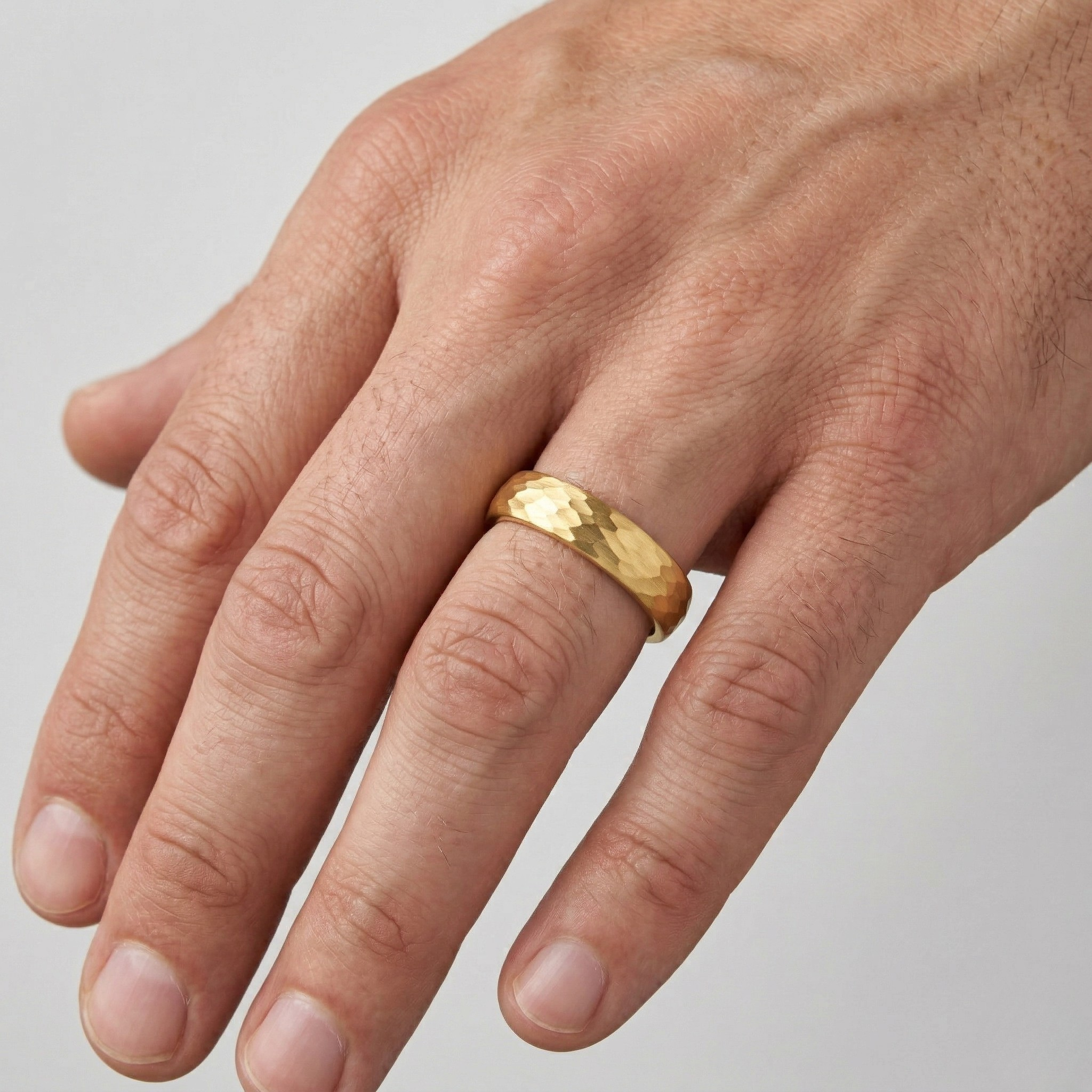 Gold Hammered Texture Dome Court Wedding Band Ring Worn on Male Hand Against White Background - J. Collins Jewelry 