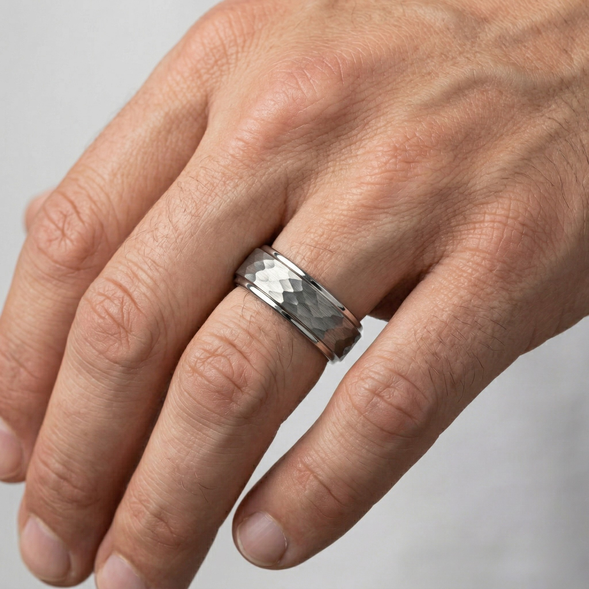 Man wearing wide silver hammered texture band ring with polished step edges on ring finger, men's statement wedding ring - J. Collins Jewelry 
