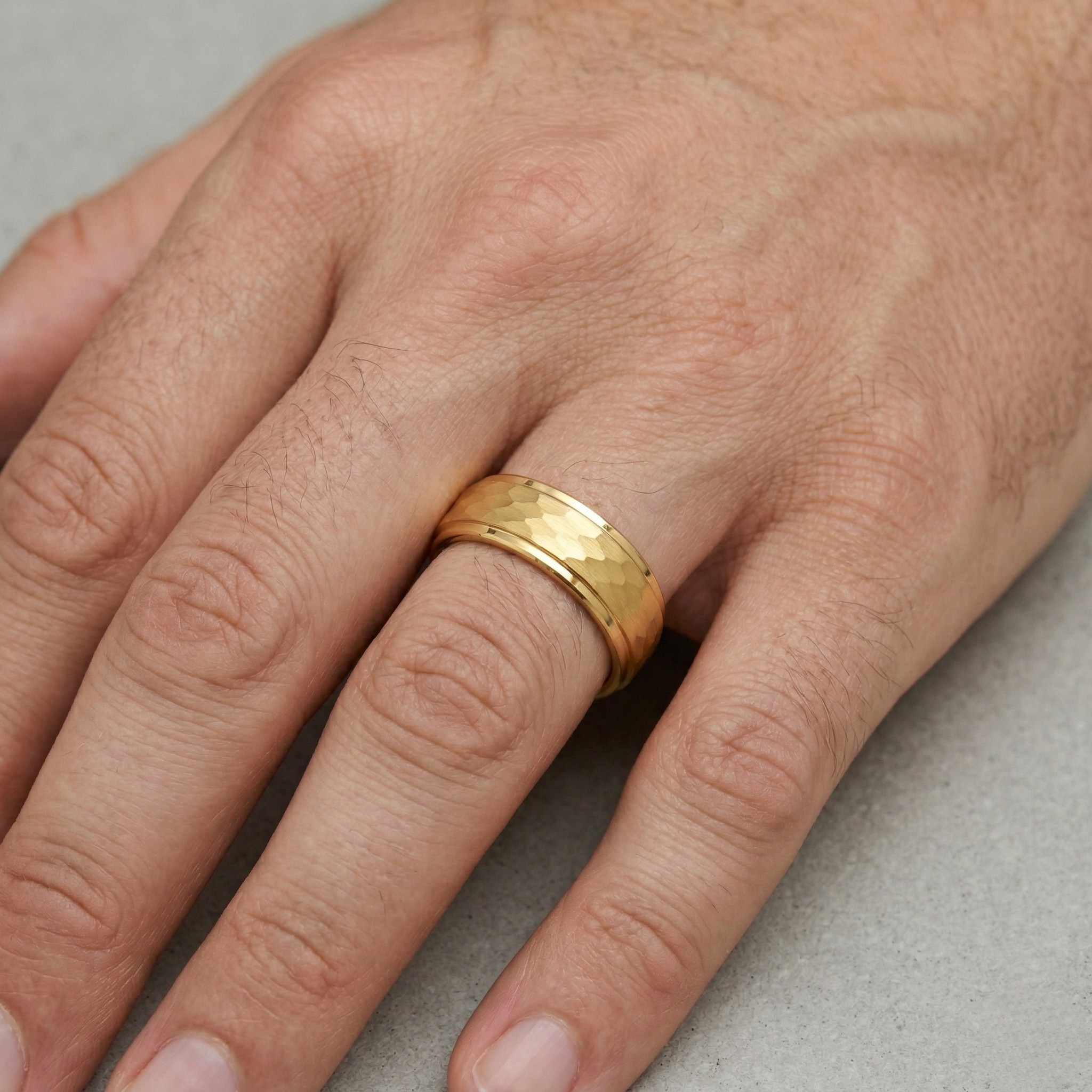 Man wearing wide gold hammered finish band ring on ring finger, men's statement wedding or fashion ring. J. Collins Jewelry 