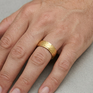 Man wearing wide gold hammered finish band ring on ring finger, men's statement wedding or fashion ring. J. Collins Jewelry 