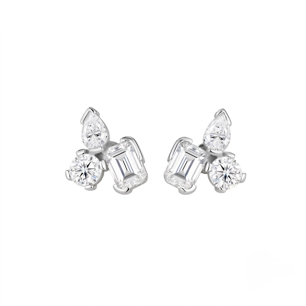 A pair of white gold stud earrings featuring a cluster of clear gemstones, including a marquise-cut stone, a round-cut stone, and an emerald-cut baguette stone, set against a plain white background - J.Collins Jewelry