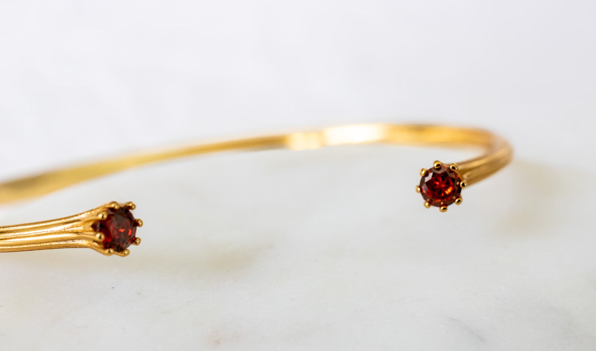 Gold bracelet with garnet stones on a white background - Valora Cuff - JCollins Jewelry 