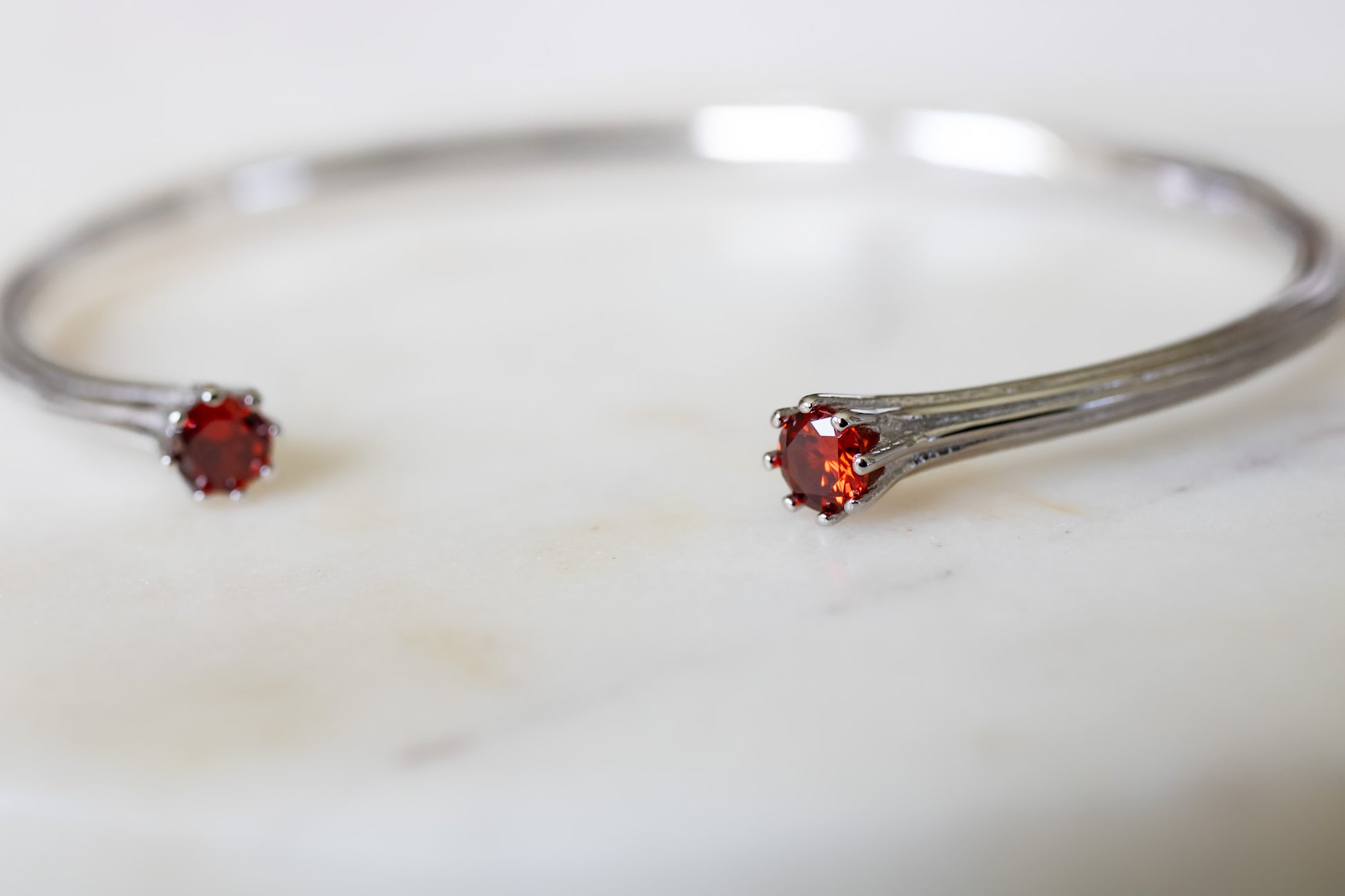 Silver bracelet with red gemstones on a light background  - Valora Cuff - JCollins Jewelry 